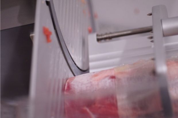 Meat slicer cutting raw meat