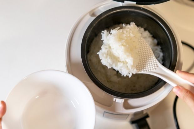 Person scooping rice out of rice cooker that doesn't take long to cook rice