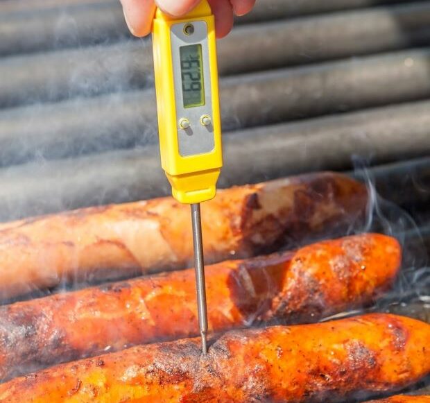 Person using thermometer to check if sausage is cooked