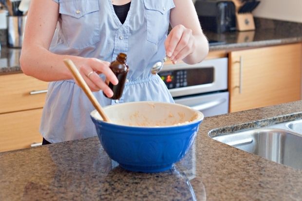 Woman adding vanilla extract to bowl after learning how to make vanilla emulsion