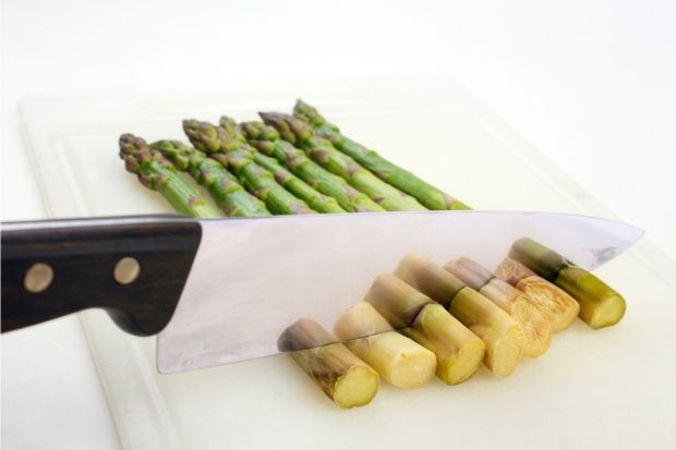 Asparagus being cut with knife after cook learned what part of asparagus you do eat
