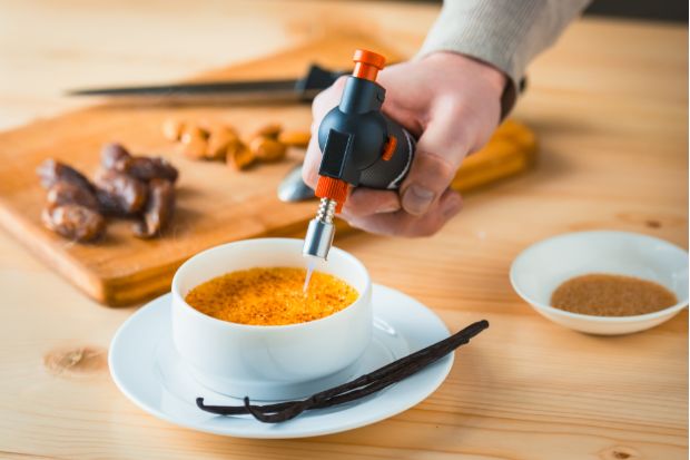 Chef using blowtorch on curdled creme bruleee