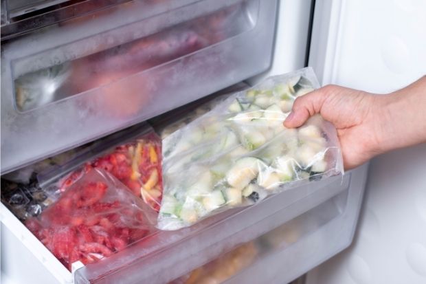 Person taking out freezer bag full of frozen vegetables from the freezer after learning about the difference between freezer and storage bags
