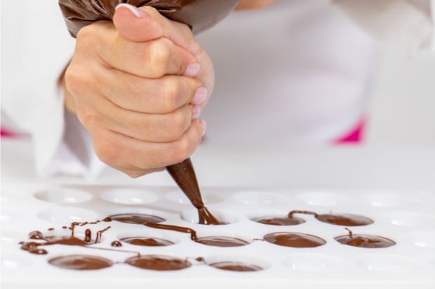 Chef squeezing chocolate into plastic chocolate molds instead of silicone molds