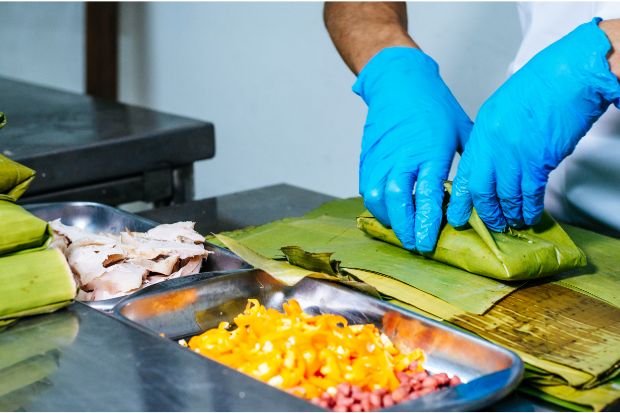 Chef using banana leaves as a substitute for corn husks when making tamales