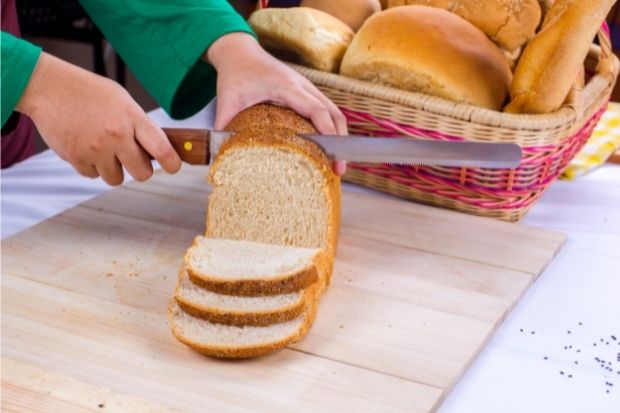Chef slicing bread with special bread slicing knife after learning if you can slice bread with a meat slicer