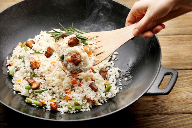 Chef scooping out fried rice from pan after learning how to keep fried rice from sticking to pan