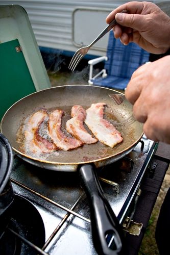 Chef frying bacon in pan after learning if you need to oil the pan for bacon