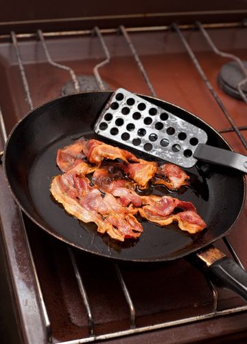 Strips of cooked bacon in a pan that lost weight when cooked