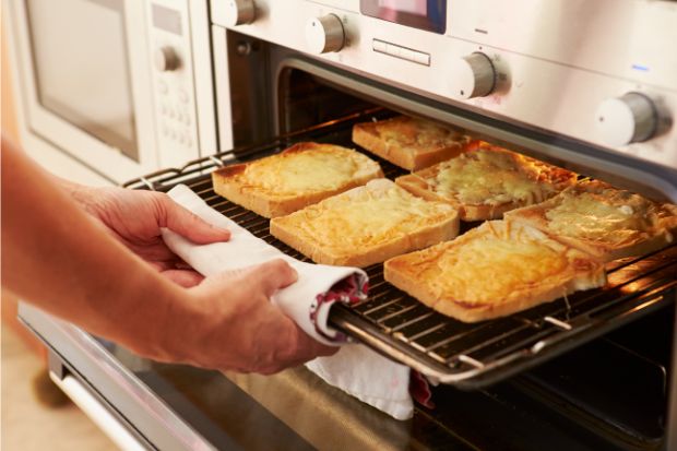 Cook removing toasted cheese from oven after learning differences between toasted cheese vs. grilled cheese