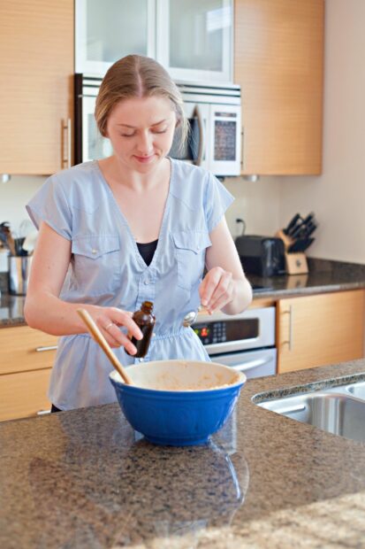 Woman adding vanilla to baking mix after learning what happens if you forgot to add vanilla