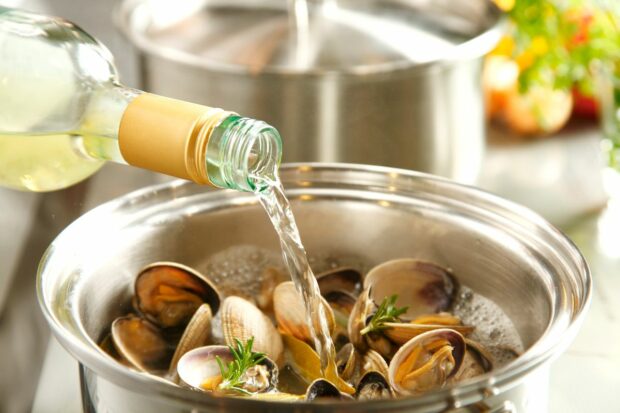 Pouring cooking wine into pot of clams